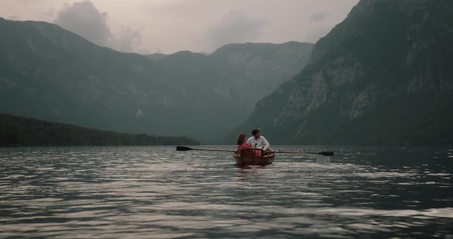 Man and woman on a date in a wooden canoe navigating through a lake during sunset