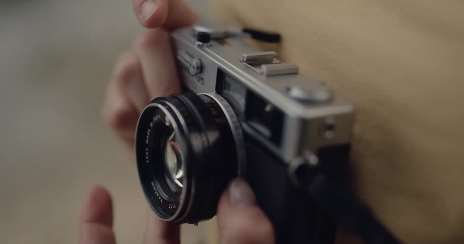 Close up of a man loading a roll and adjusting the lens on a vintage photography camera