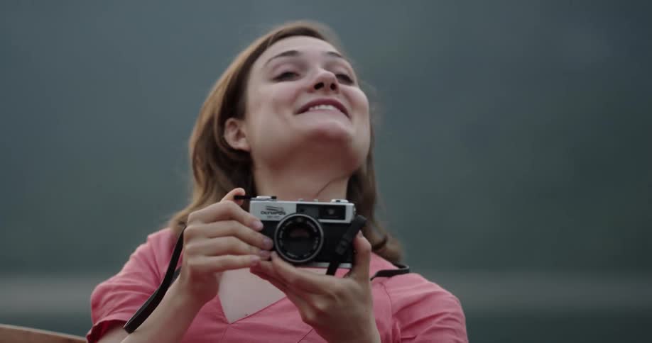 A woman is sitting down taking a picture and smiles