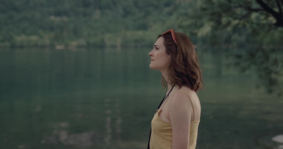 Woman standing next to a lake looking at the surroundings contemplating the view