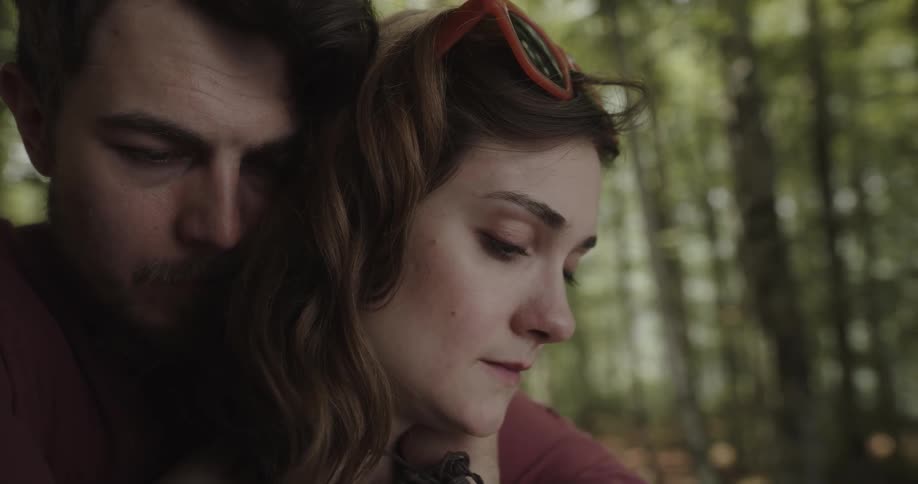 Woman and man are affectionate while standing in a wooded area