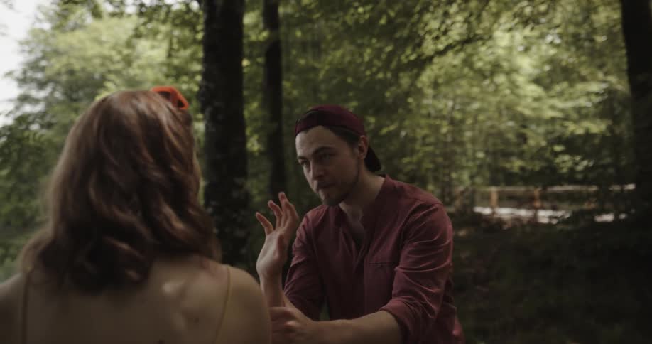 A man arguing with a woman attempts to hold her hand after she throws his phone only to be pushed away and slapped