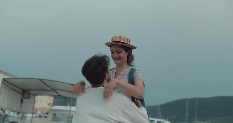 A man picks up his girlfriend and twirls her around while on a pier