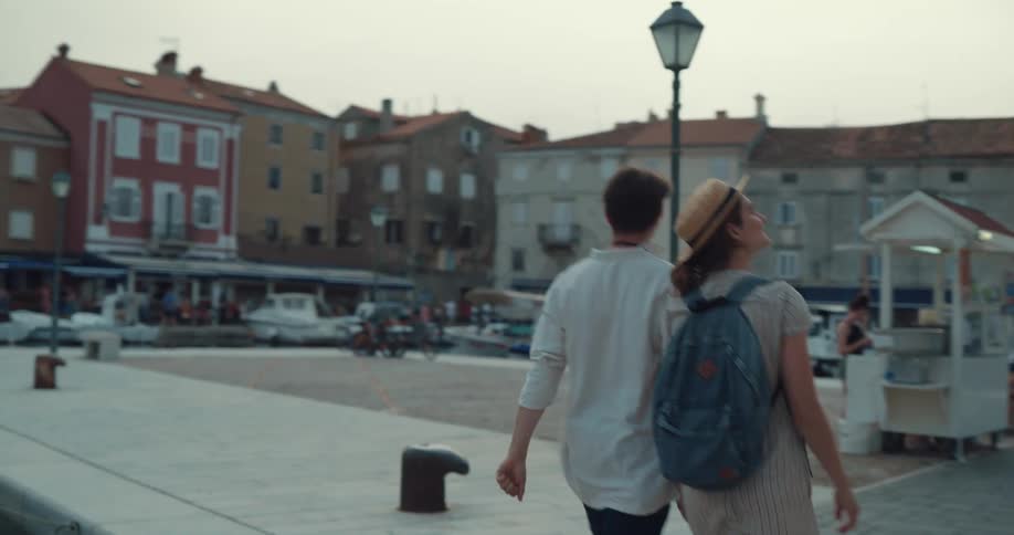 Couple walk hand in hand along waterfront in seaside town