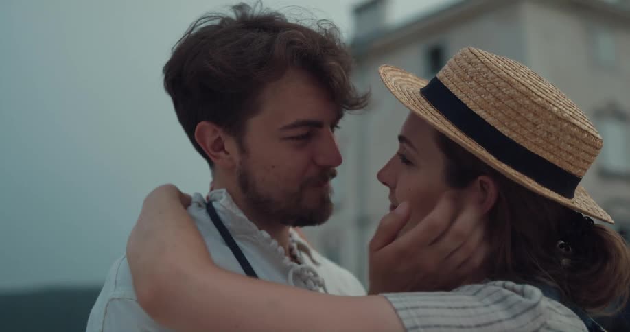 A woman and man are kissing outdoors near a city