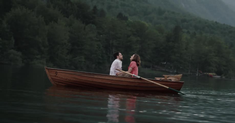 Romantic couple sitting in a row boat on a lake kissing