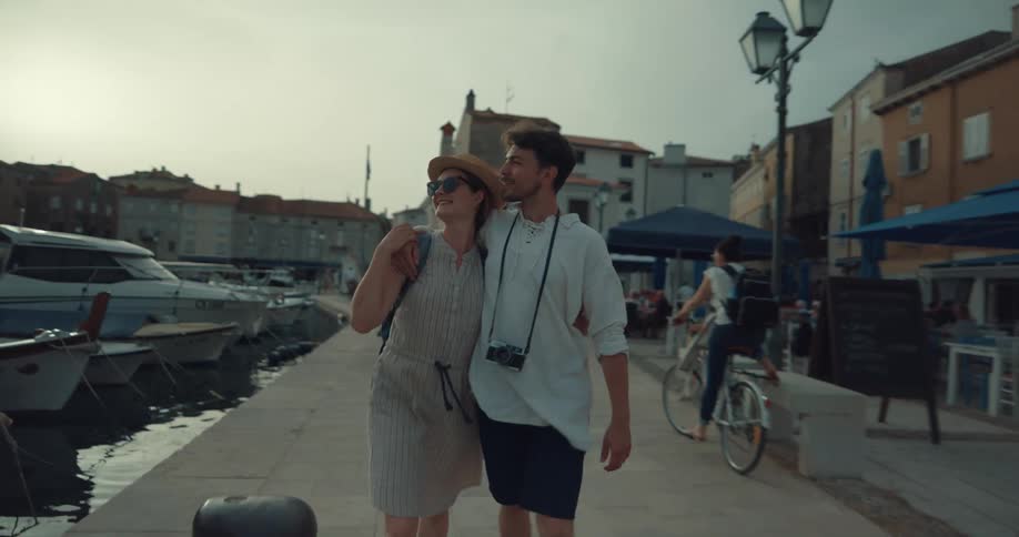 Happy couple holding hands walking along the marina on vacation