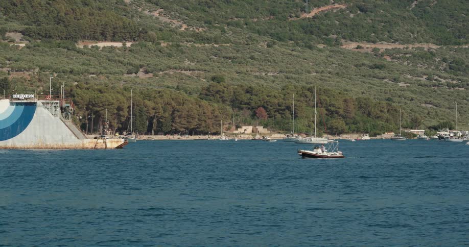 Boat sailing on the calm ocean surface near the coast in front of the mountains
