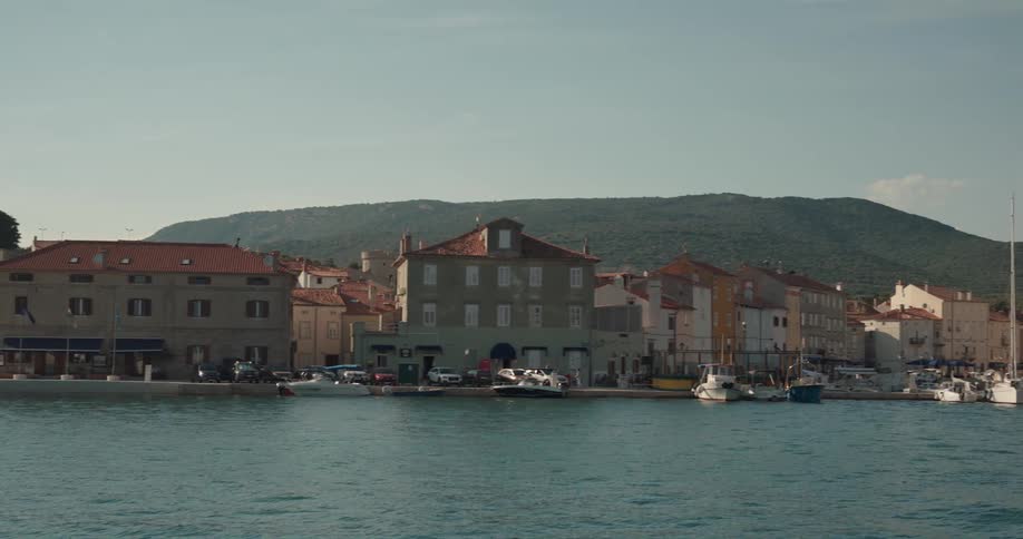 Boats on a dock in front of a small town close to the mountains at morning