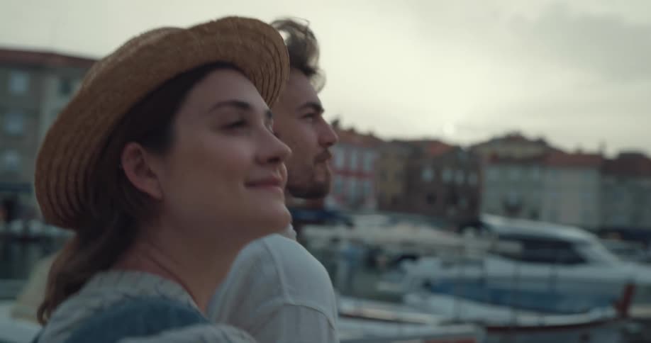 Young happy couple on vacation talk while walking near a pier in a small town