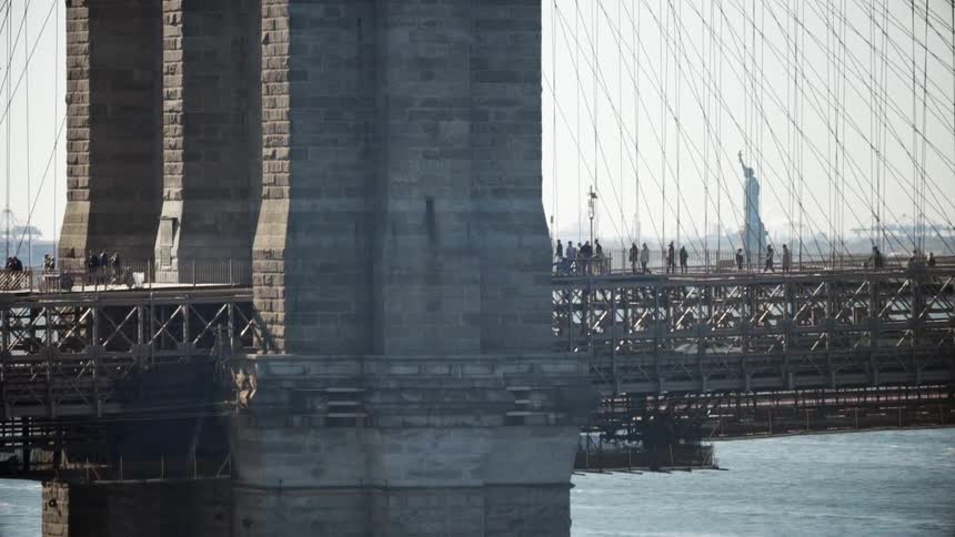 A large bridge has people walking and cars driving on it
