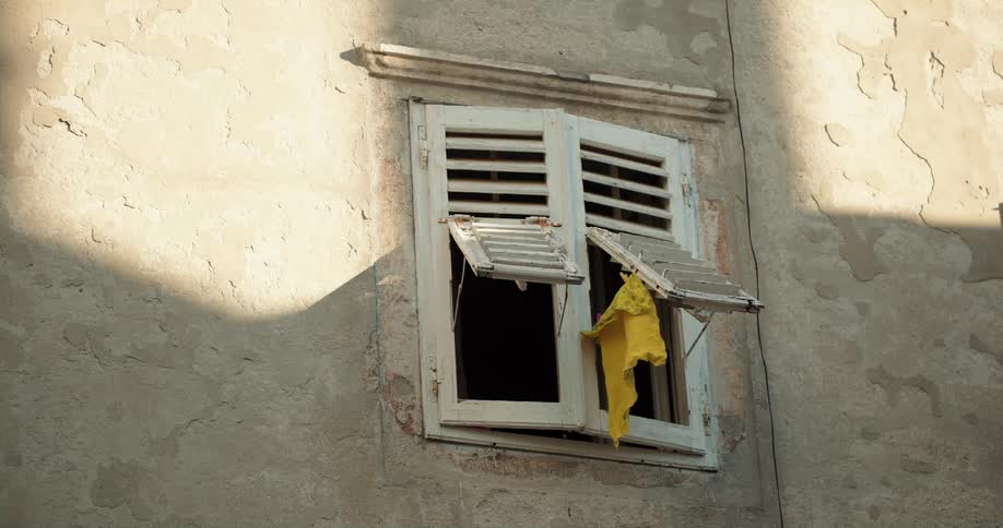 A piece of yellow cloth hanging from the window of an old building