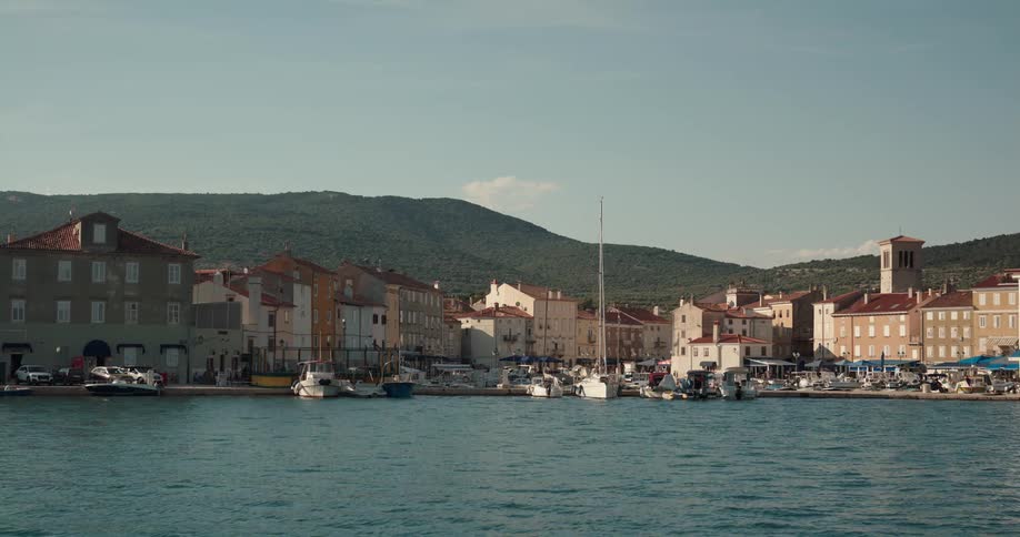 Boats on a dock in front of a small town close to the mountains at morning