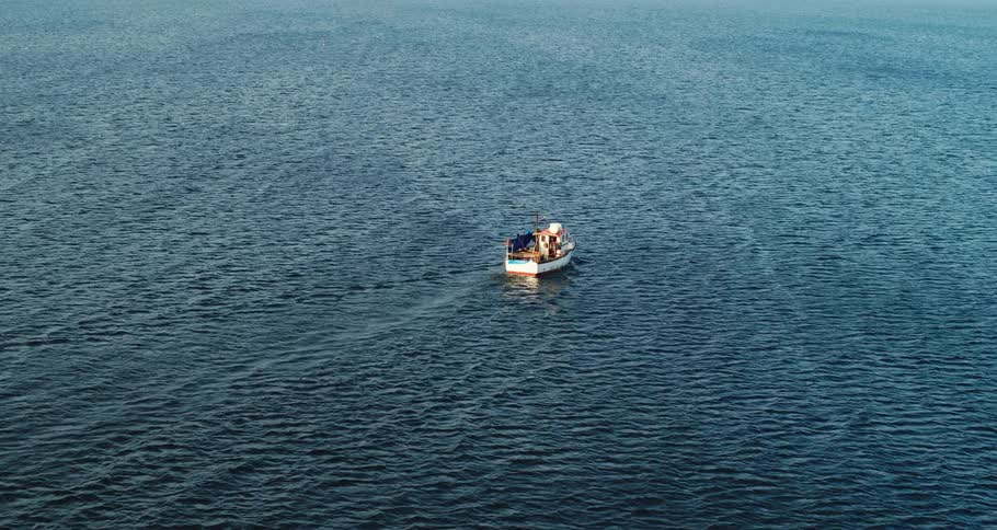 A boat is sailing in open water as light reflects the ripples and waves in the ocean