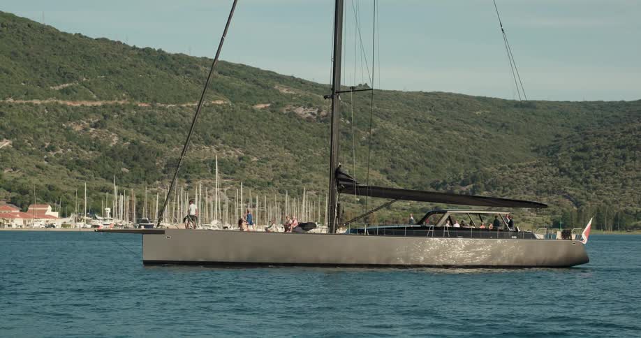 A group of people ride a large boat along the coast during the day