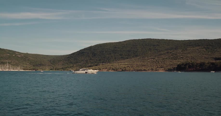 A large boat travels across the ocean just off the coast during the day