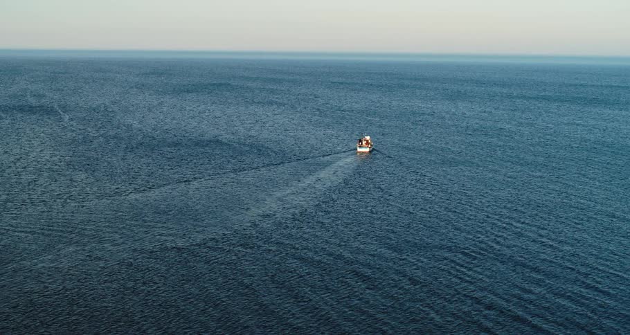 A boat is sailing in open water as light reflects the ripples and waves in the ocean