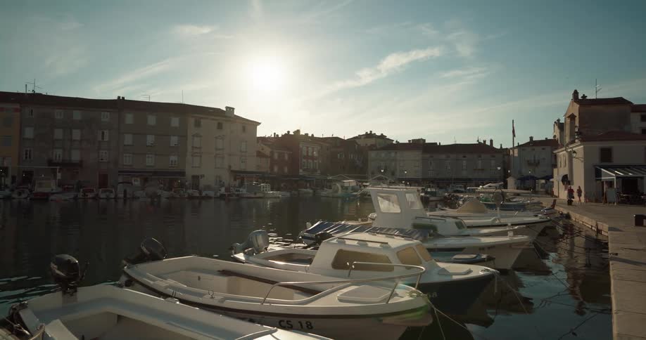 Boats docked in a marina in a town on a bright day