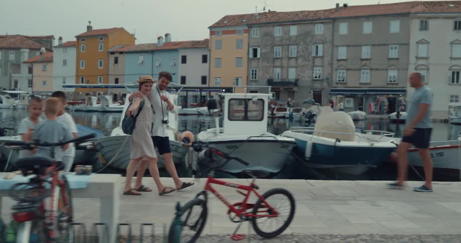 A couple walk with their arms around each other down a pier