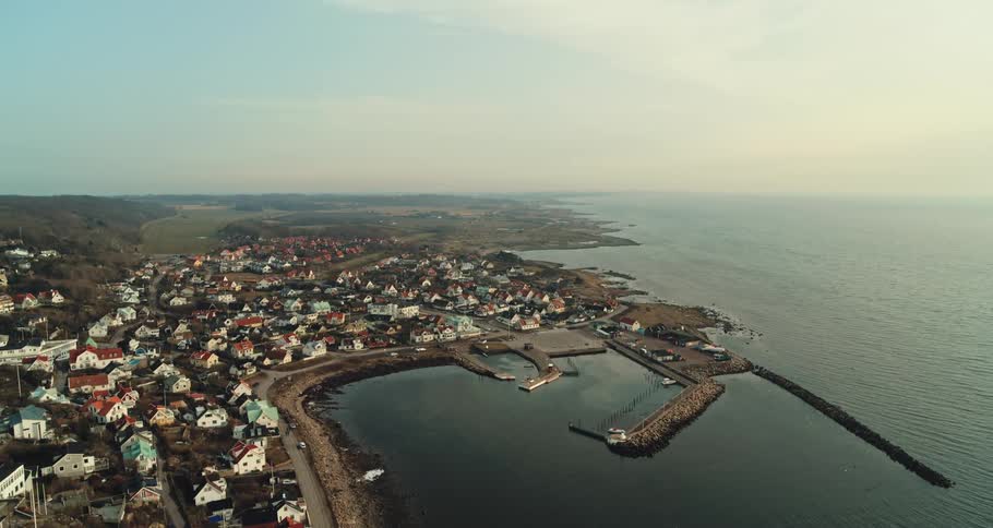 Aerial view of the bay in front of a a calm small coastal town close to the ocean at morning
