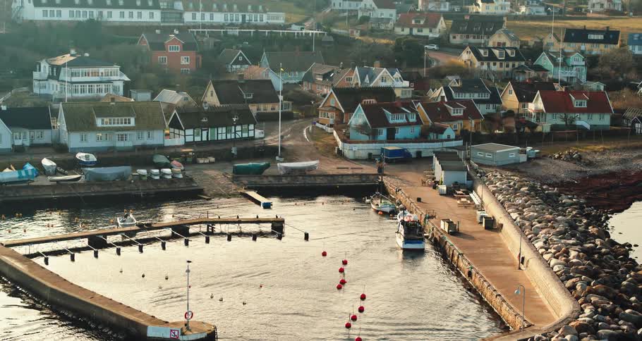 Aerial view of a boat docking on a small pier on a coastal town at morning