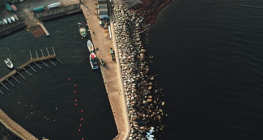 Boats sit next to a pier on the ocean