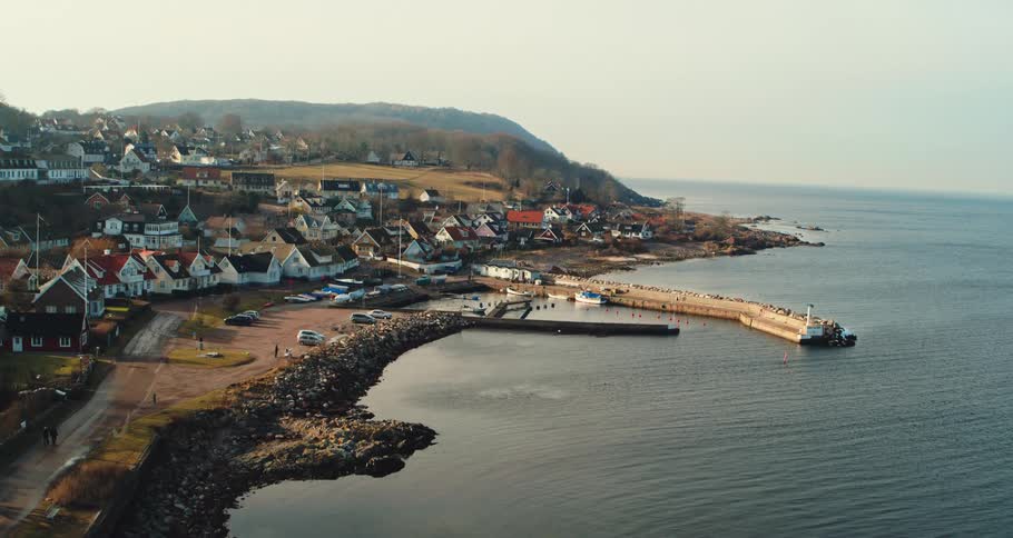 People walk along road and on beach in seaside town on misty day