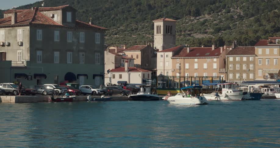 Boat moving towards a dock on a small waterfront town at daytime