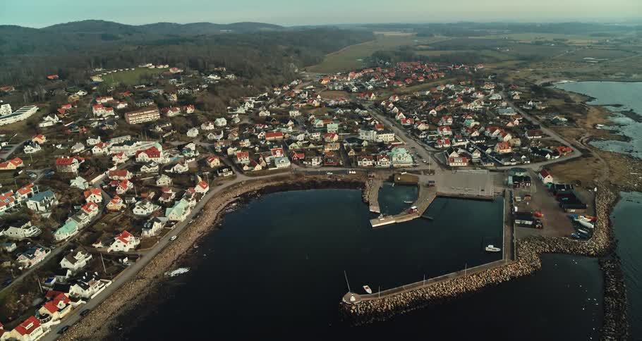 Town sits between water and forest with mountains on the horizon