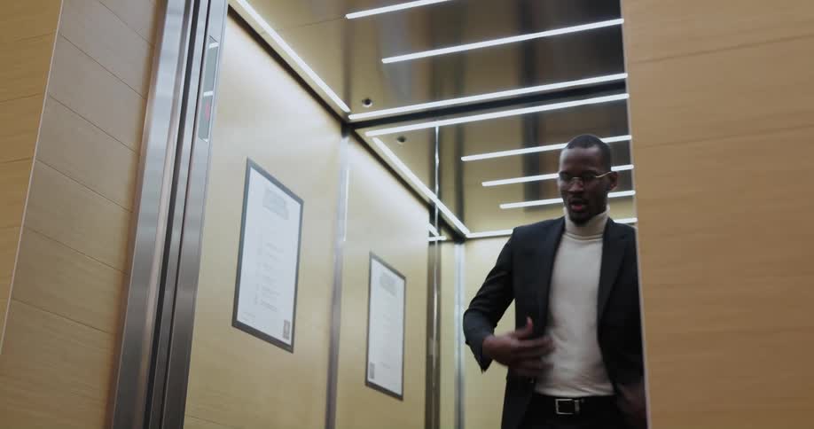 A man walks into an elevator and adjusts his jacket as the elevator doors close