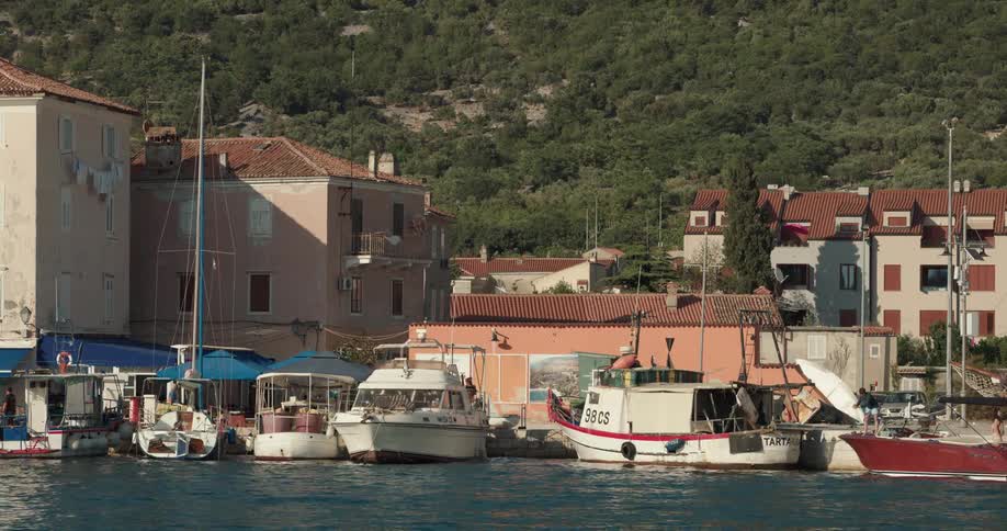 Boats docked in the water with people walking behind them