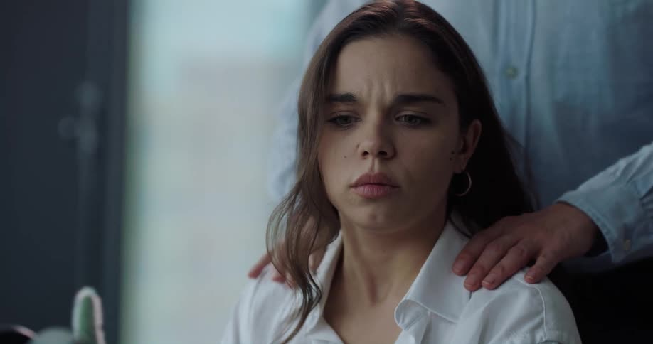 Woman disturbed by male colleague massaging her shoulders at the office