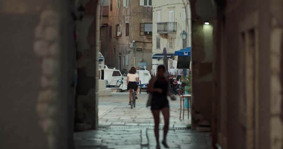 Woman riding a bicycle through an alleyway on a small town
