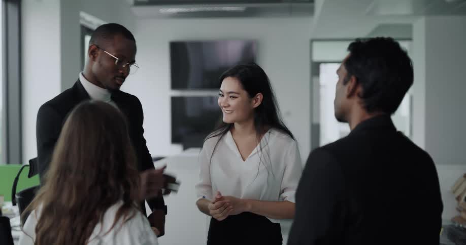 Coworkers stand in office celebrating and smiling