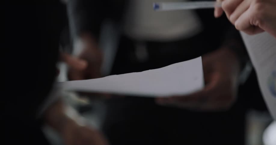 Four people standing in a circle having a meeting on an office space holding some papers and gesticulating
