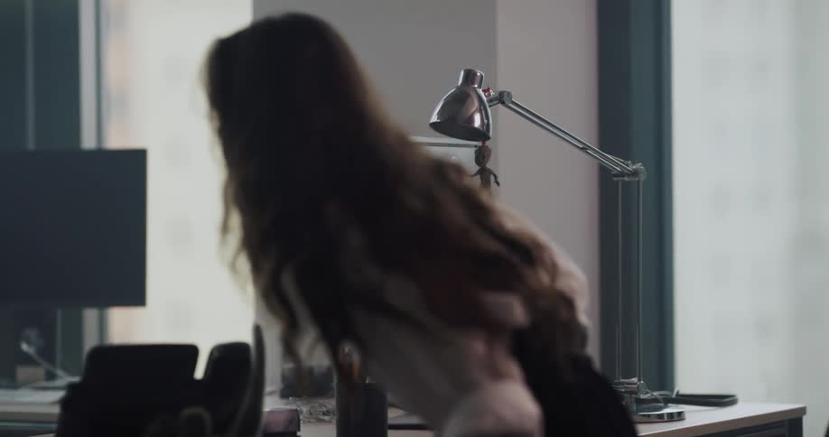 Boss sitting on his chair on his office asking to his female employee to sit down on the other side of the table and then standing up to give her a shoulder massage
