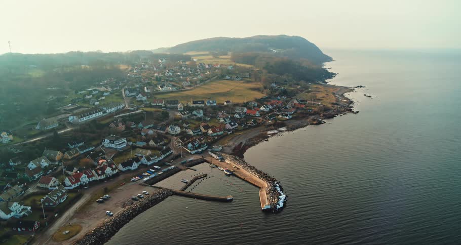 Aerial view of coastal town with pier and detached houses at sunset