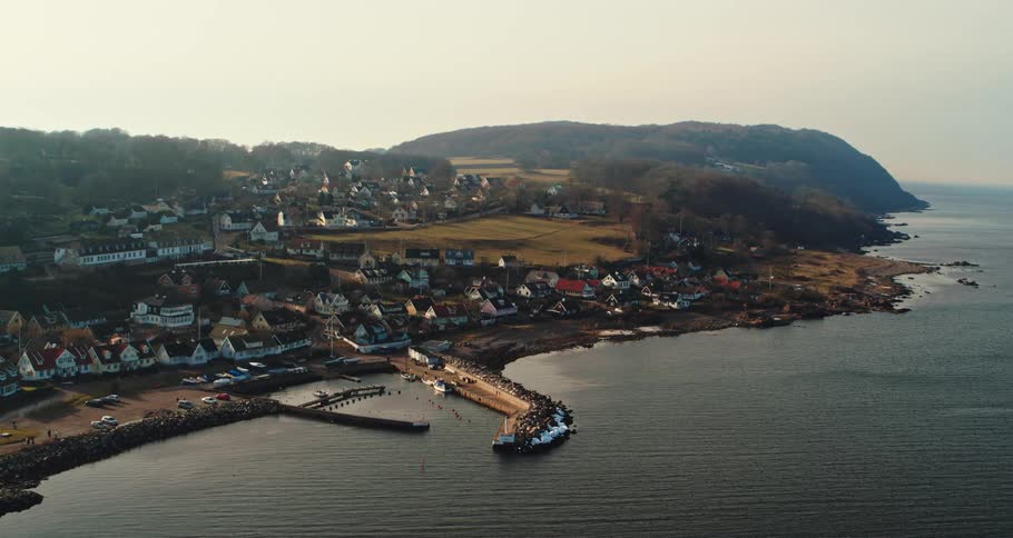 Aerial view of the bay in front of a a calm small coastal town close to the ocean at morning