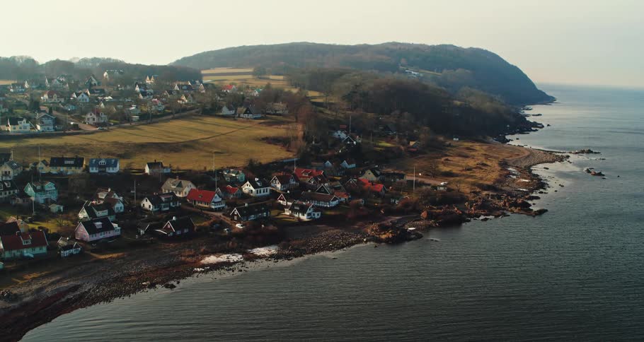 Aerial view of coastal town with pier and detached houses next to ocean