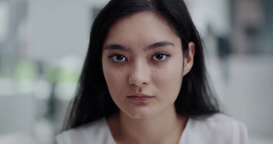 Young asian woman with black hair looks up at the camera