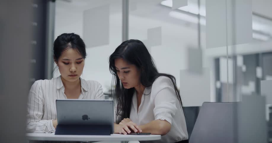 Two coworkers looking at a laptop