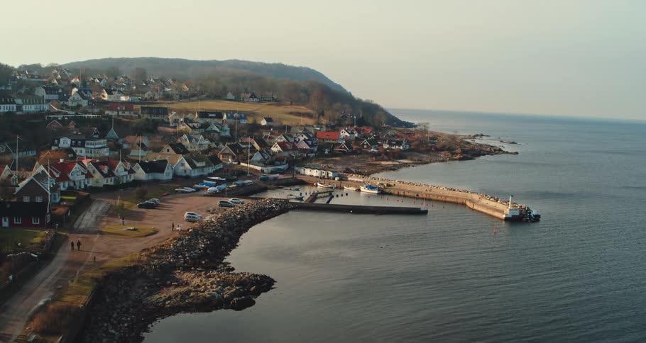 People walk on a trail that runs past a beach and neighborhood along the coast