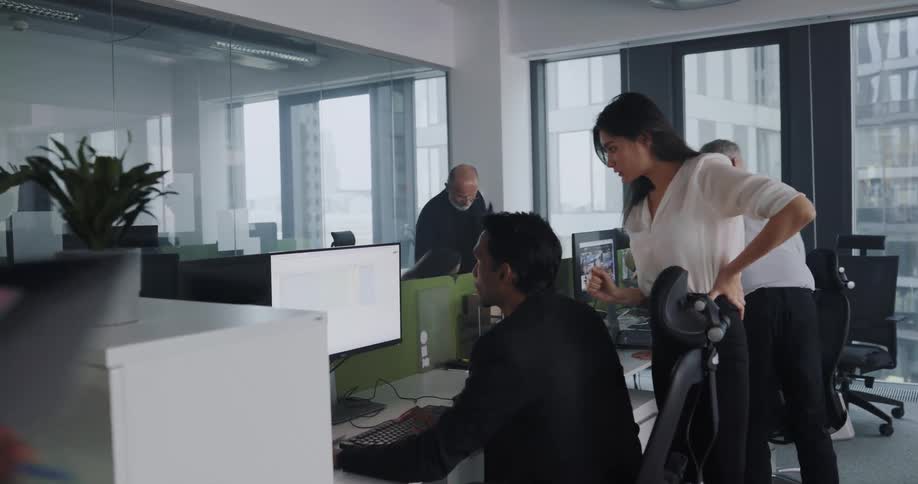 Supervisor talking to a worker at his desks in a busy office in the city