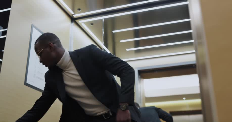 Black man wearing formal clothes entering an elevator in a hurry