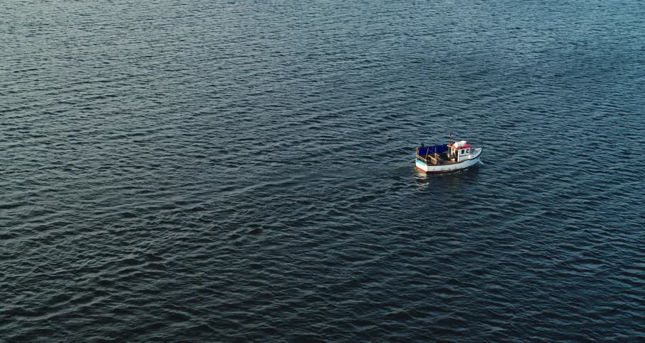 A small fishing boat steadily moves across the ocean water