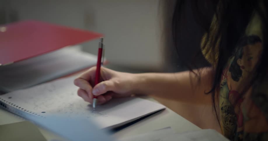 A woman takes extensive notes while doing homework at her desk