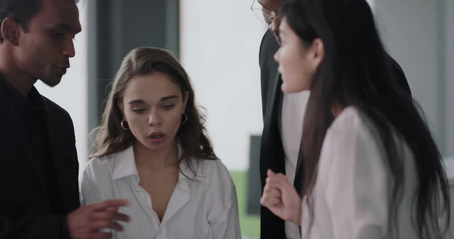 A group of people speak with one another while gathered around a paper in an office