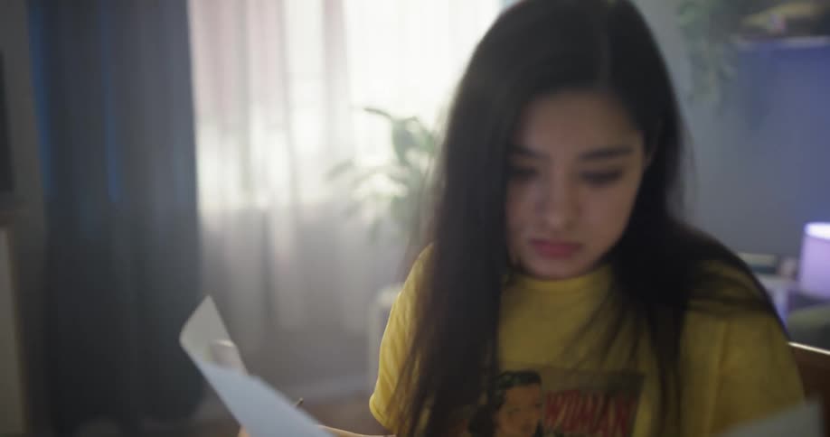 A woman sitting at a desk at home going through her notes and studying