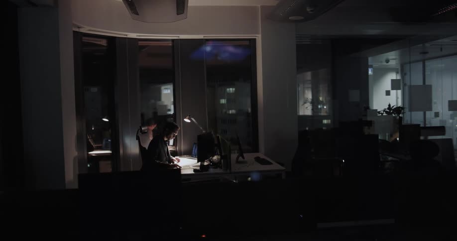 Man sitting at a desk in the dimly lit office working alone at night
