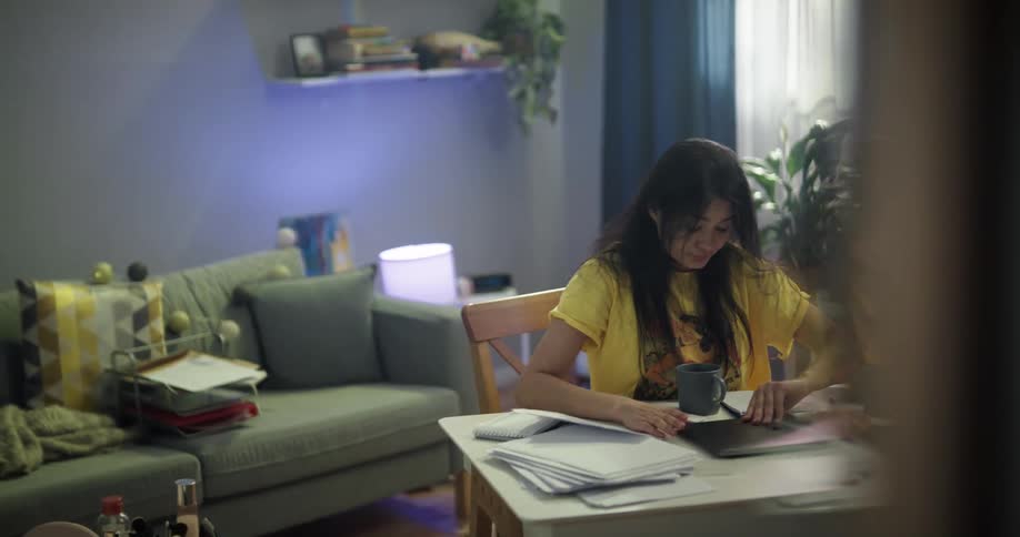 A woman sits on the floor of a living room surrounded by papers and a laptop